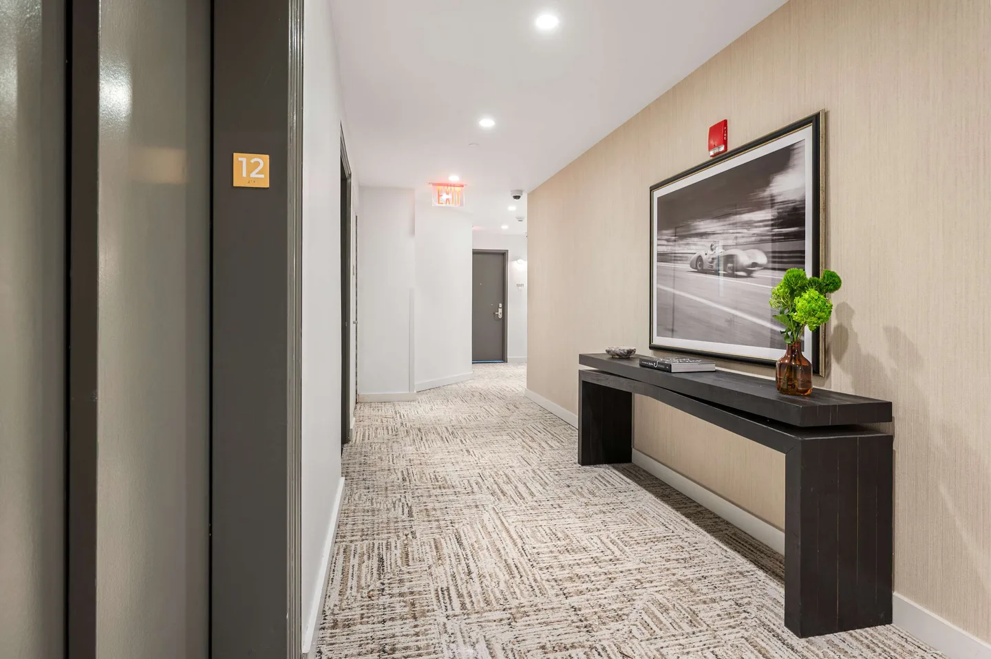 A hallway with a carpeted floor and a black console table.
