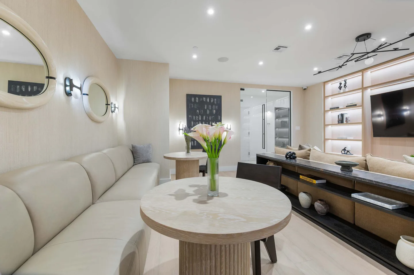A living room with a beige couch, round tables, and a TV.