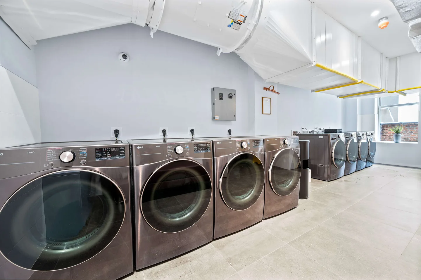 A row of stainless steel LG washing machines in a laundry room.