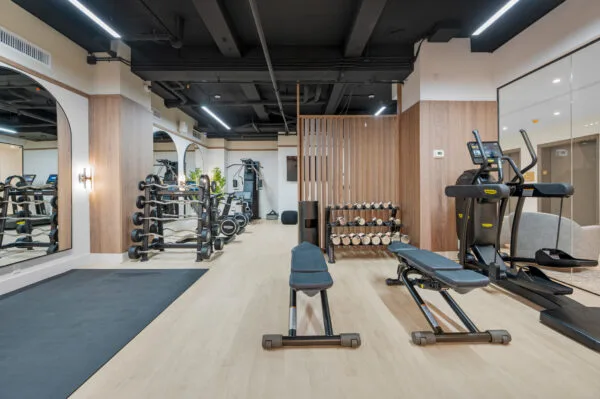 A gym with wooden floors, mirrors, and various exercise equipment.